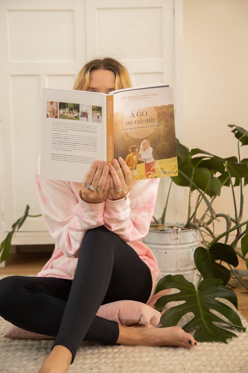 Femme qui tient le livre A go on ralentit ouvert devant son visage. / Woman holding the book A go on ralentit open in front of her face.